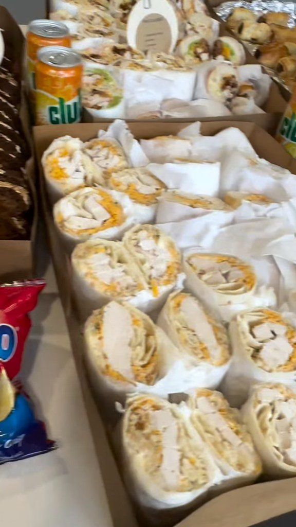 A catering platter of chicken wraps with cans of Club Orange